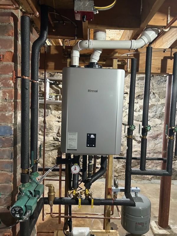 A water heater is surrounded by pipes in a basement.