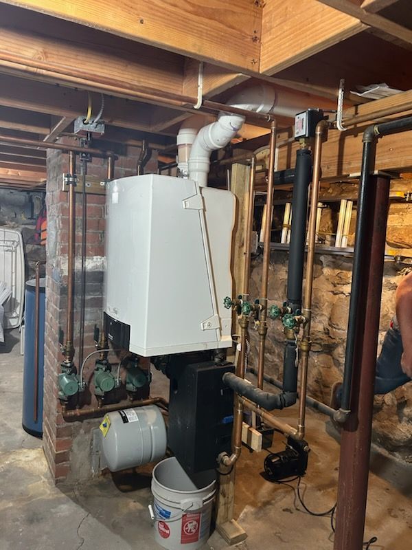 A water heater is surrounded by pipes in a basement.