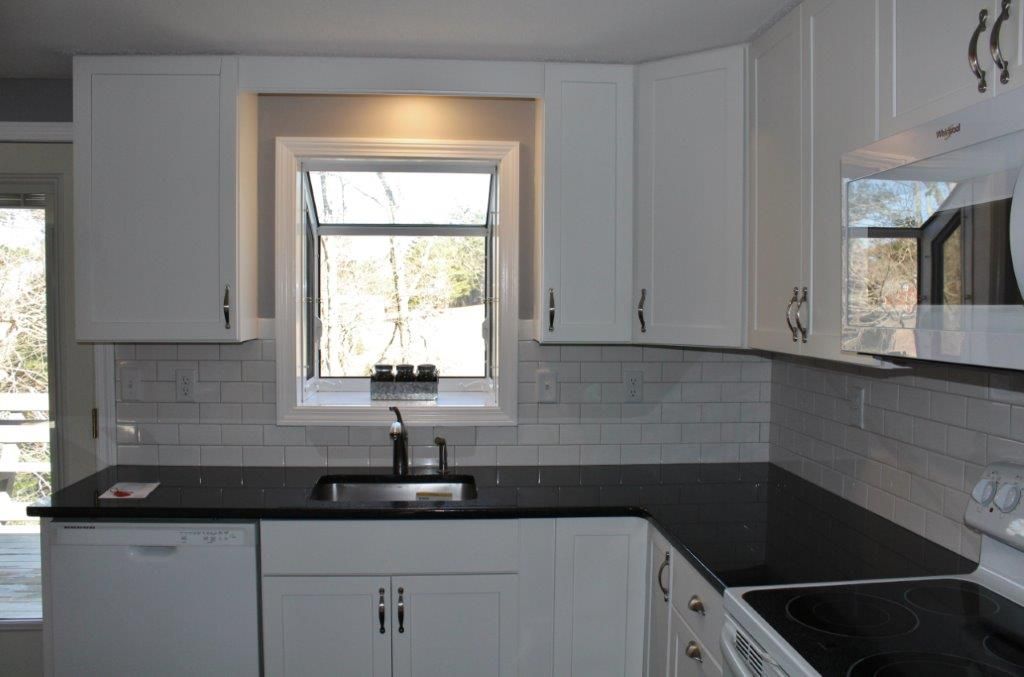 A kitchen with white cabinets and black countertops