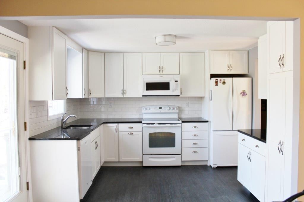 A nice-looking kitchen with white cabinets and black countertops