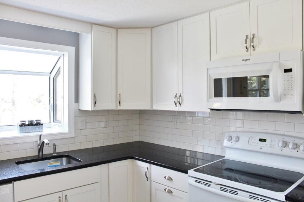 A pleasing kitchen with white cabinets and black countertops