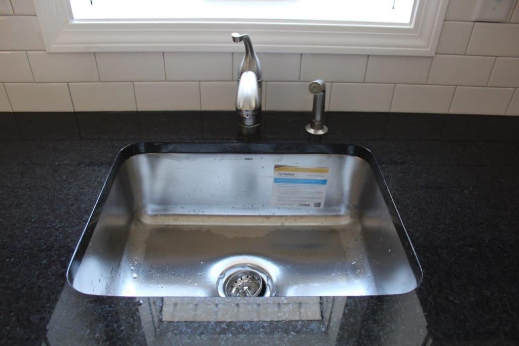 A good-looking stainless steel kitchen sink with a black countertop