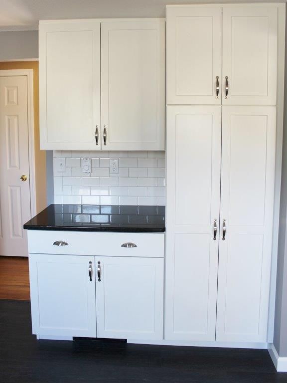 An angelic kitchen with white cabinets and a black countertop.