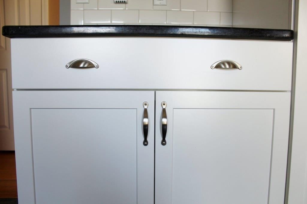 A white cabinet with two drawers and a black countertop