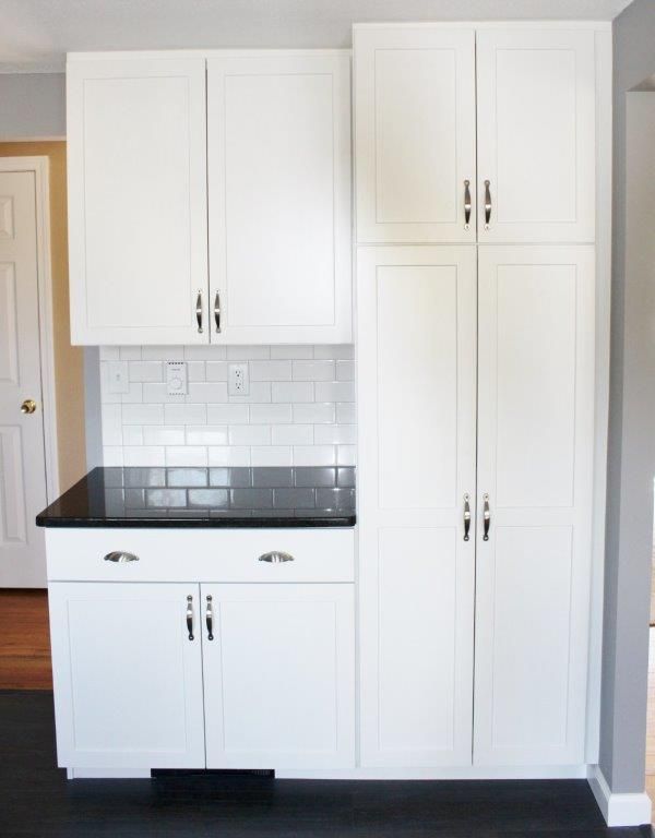 A comely kitchen with white cabinets and a black countertop