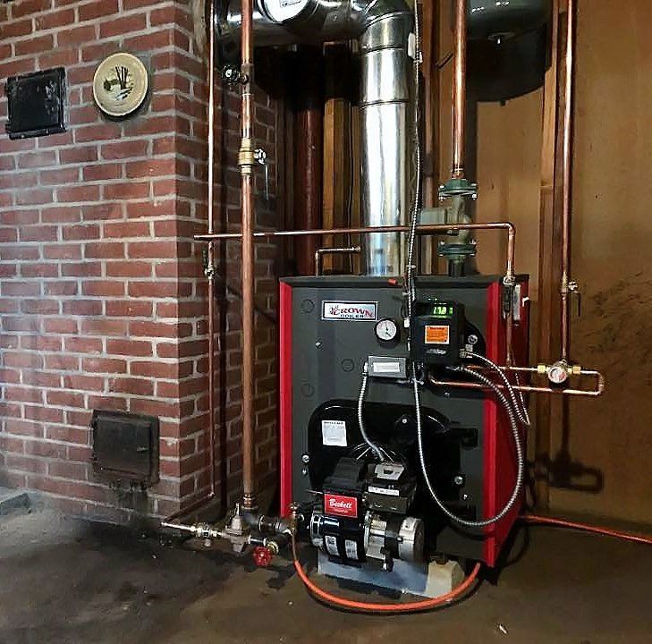 A red and black boiler in a room next to a brick wall