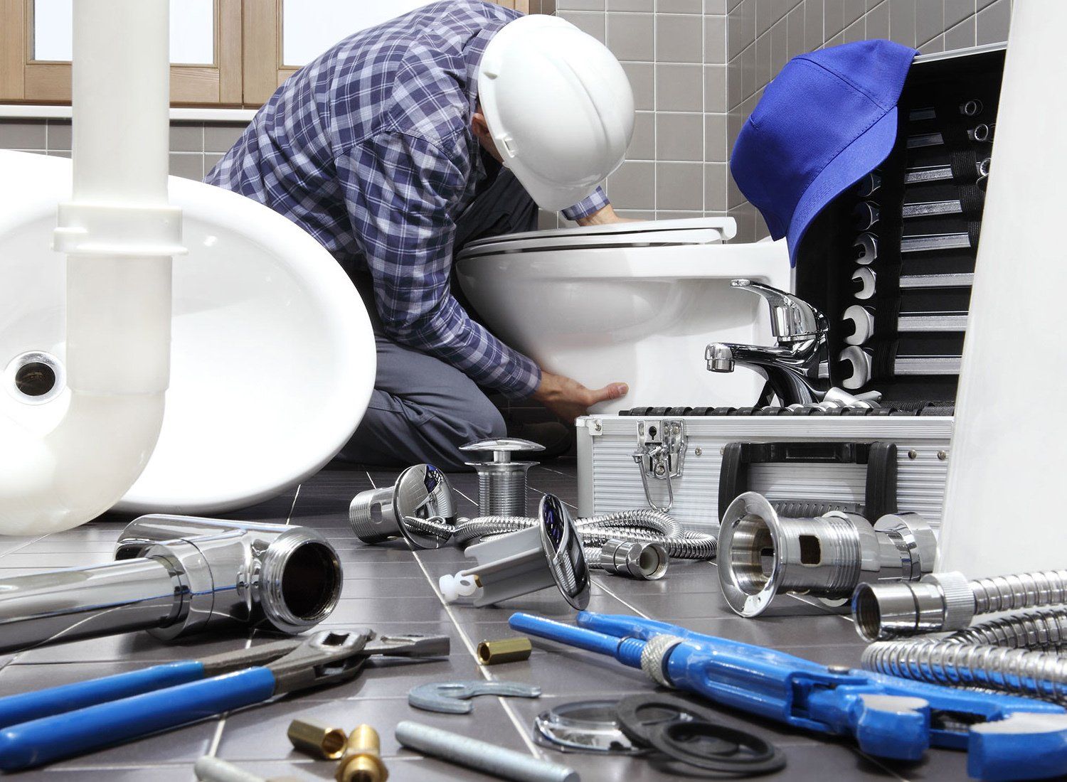 A plumber is working on a toilet in a bathroom.