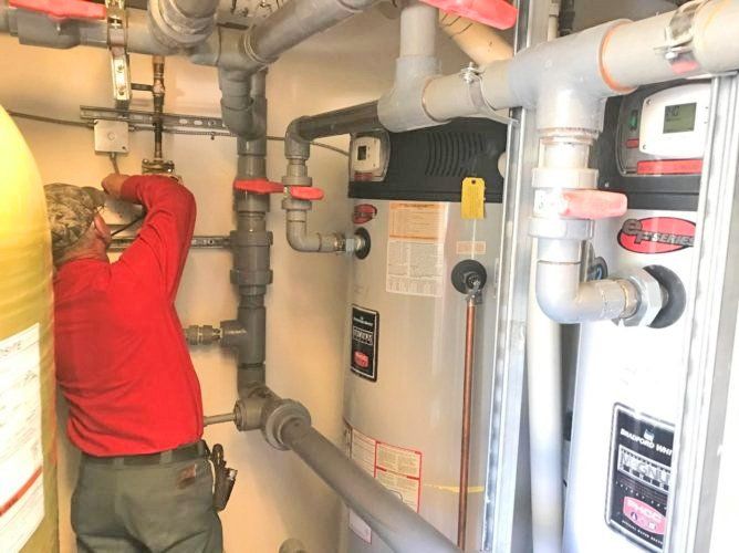 A man in a red shirt is working on a water heater