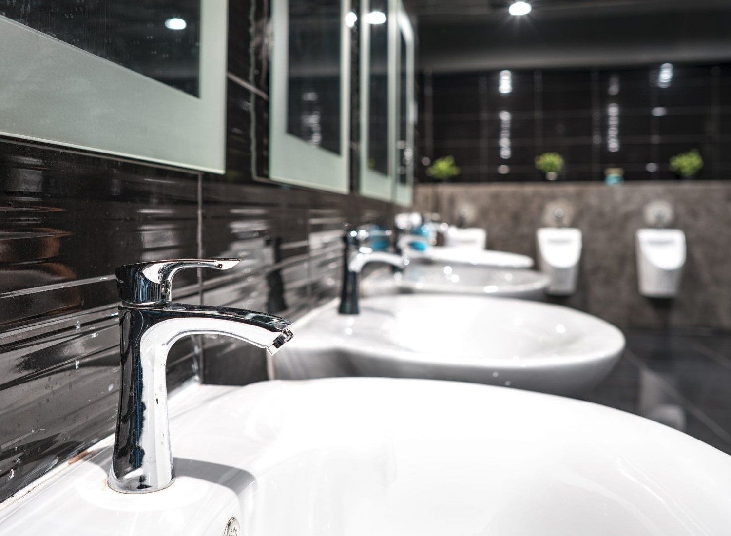 A bathroom with a row of sinks and urinals.