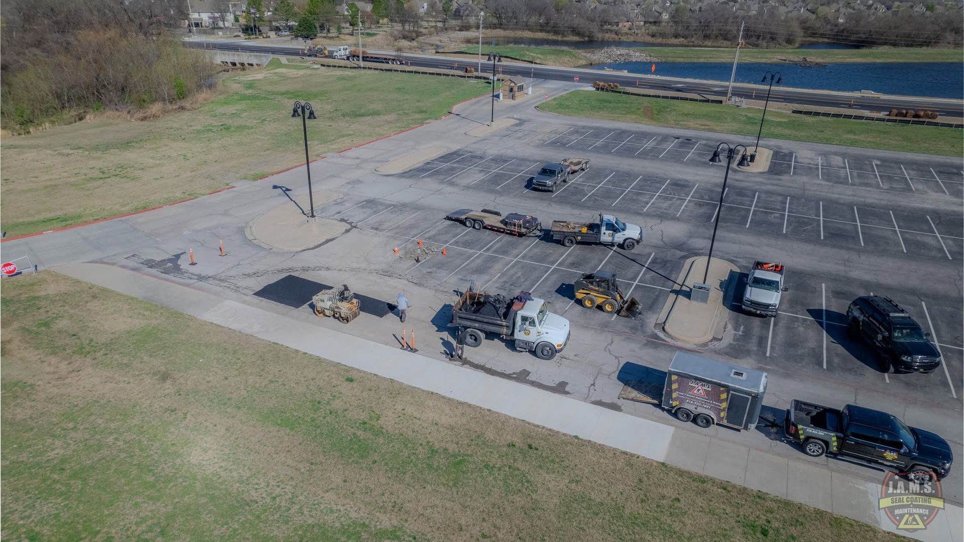 Aerial view of a mostly empty parking lot with several parked cars and a few light poles.