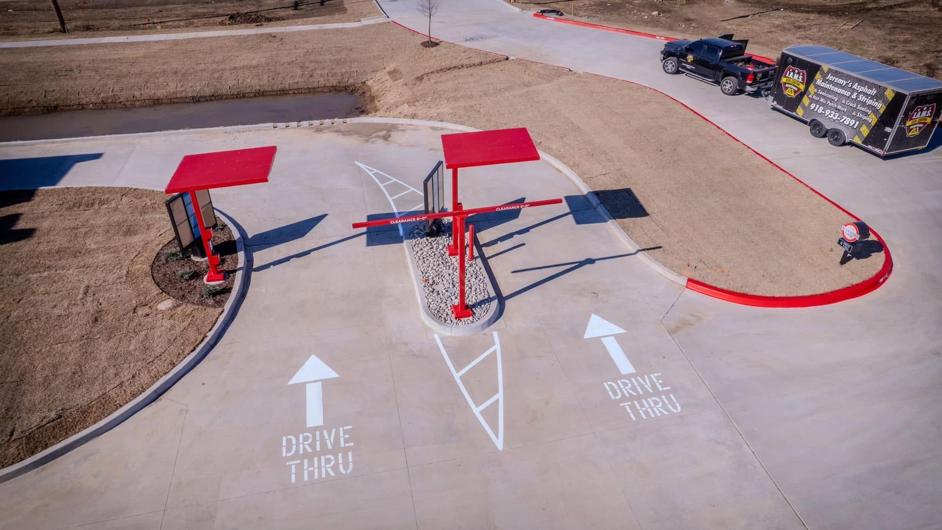 Outdoor gas station with red-roofed pump islands and directional arrows painted on the concrete.