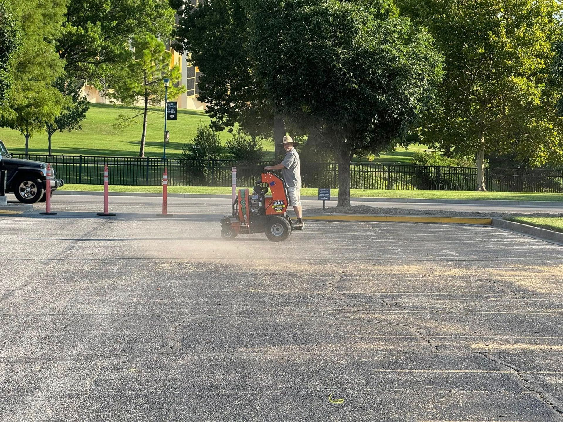 Person on a red mobility scooter driving across a gravel parking lot near a park.
