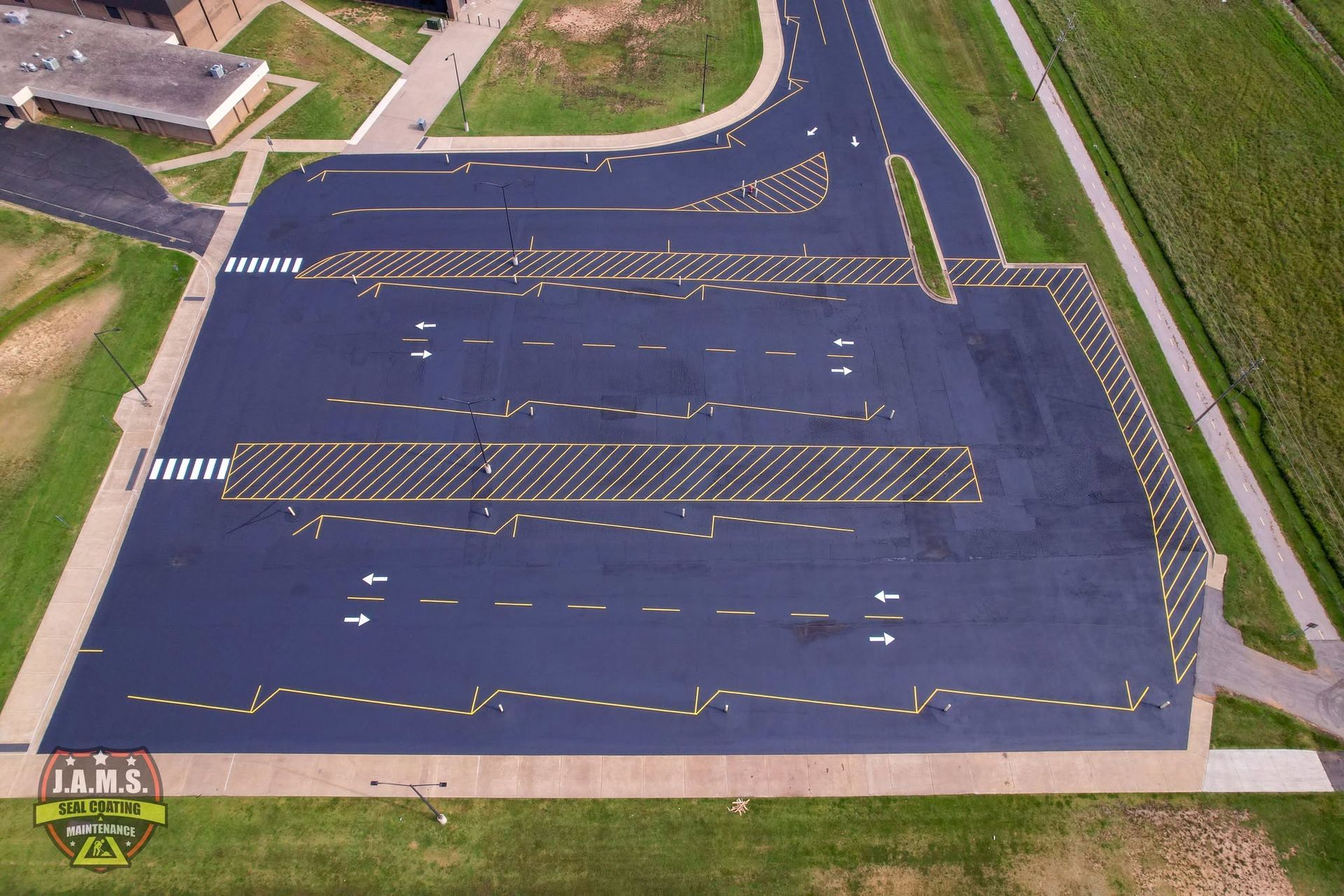 Aerial view of an empty parking lot with faded white lines and a road curving beside it