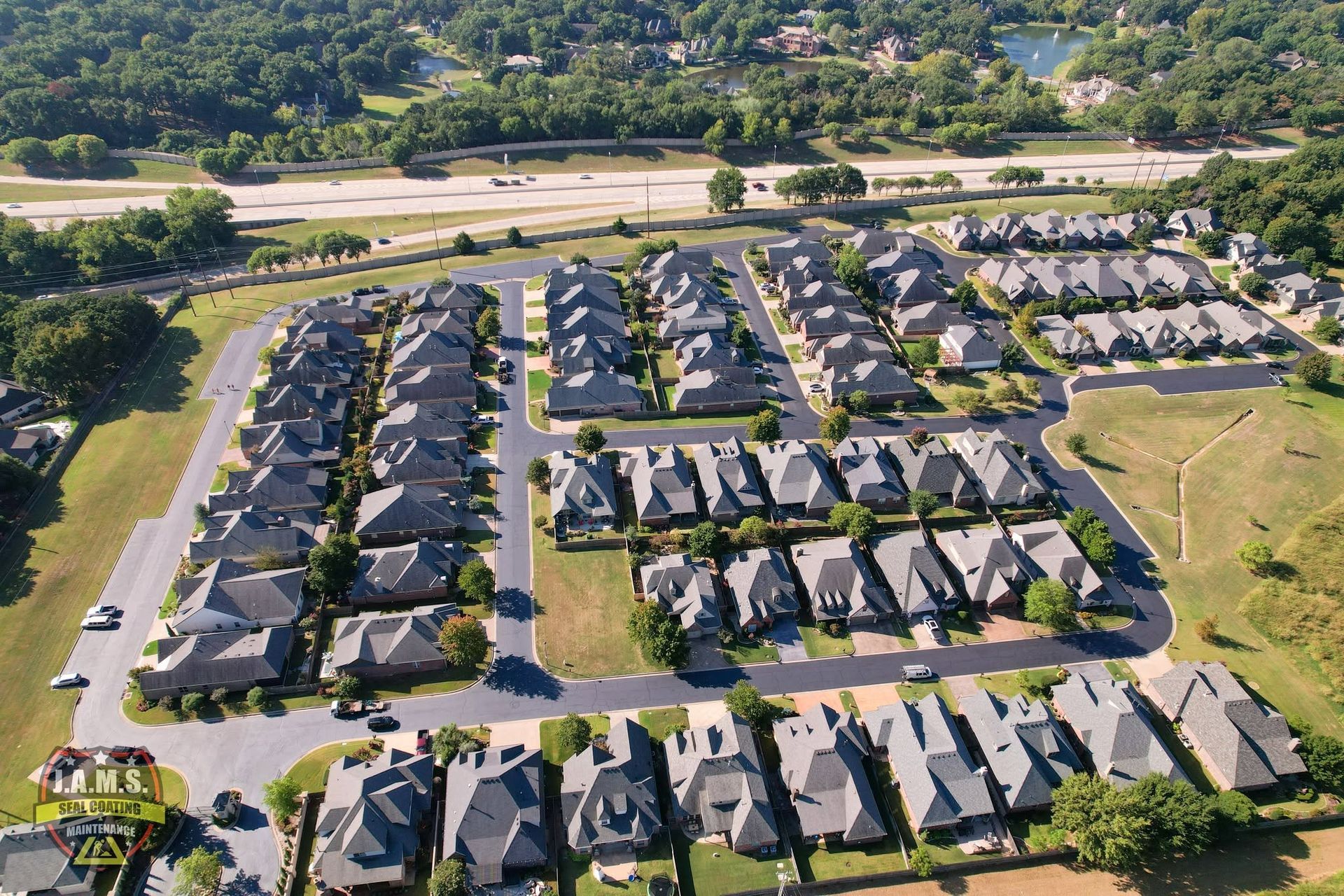 Aerial view of a suburban neighborhood with rows of houses, streets, and nearby green fields.