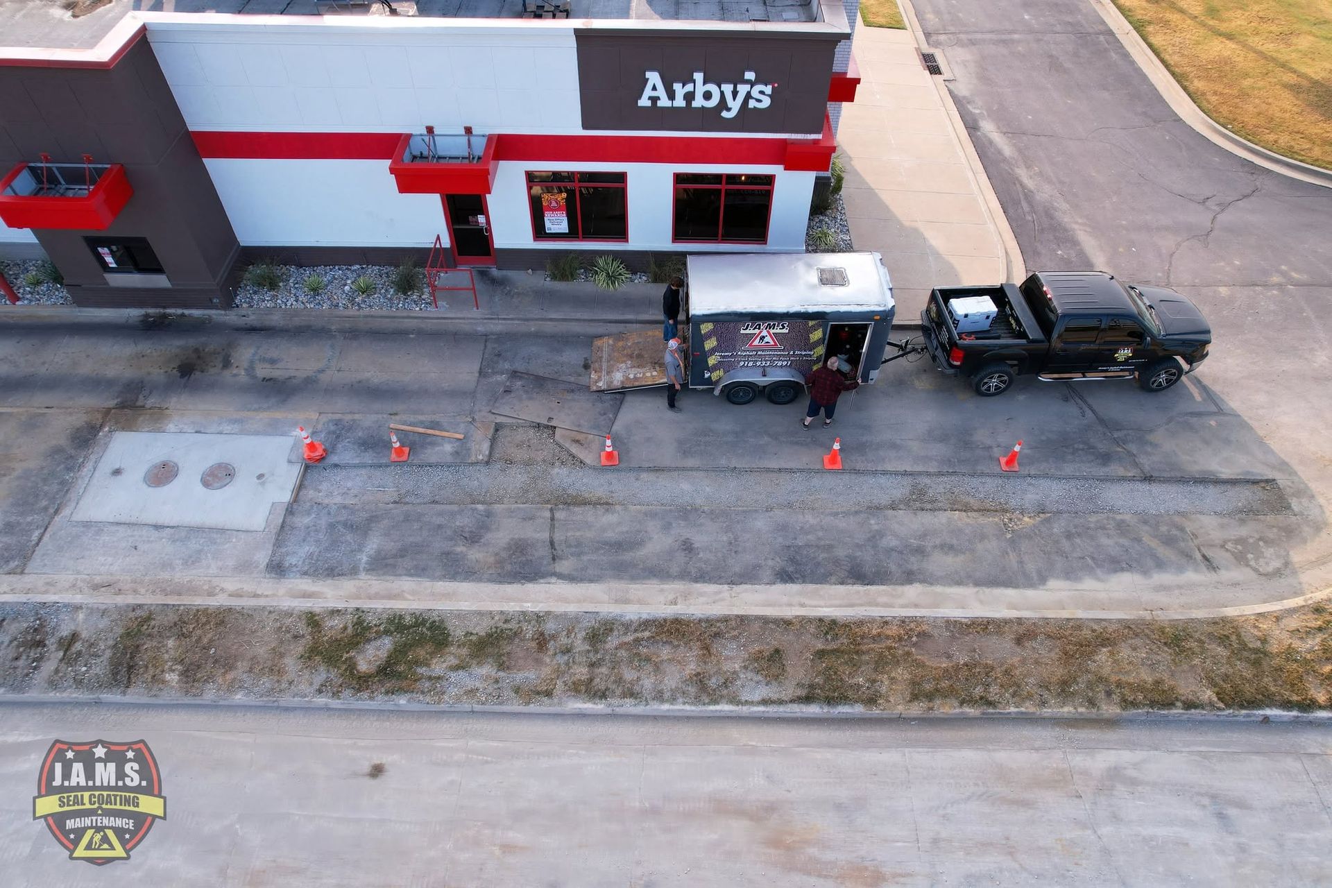 Arby's storefront with a trailer, black pickup truck, and orange cones in the parking lot
