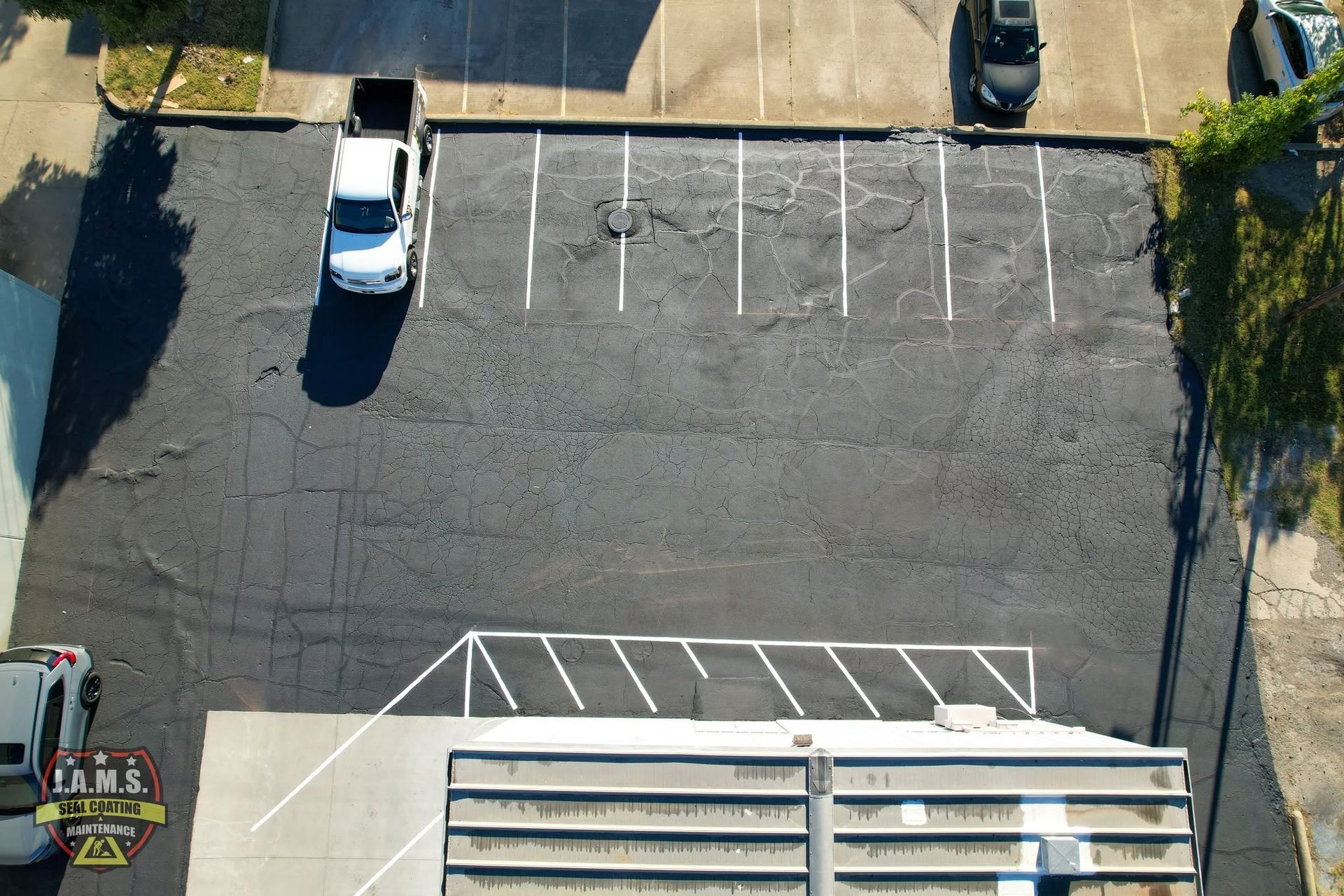 Aerial view of an empty parking lot with a white SUV and marked parking spaces.