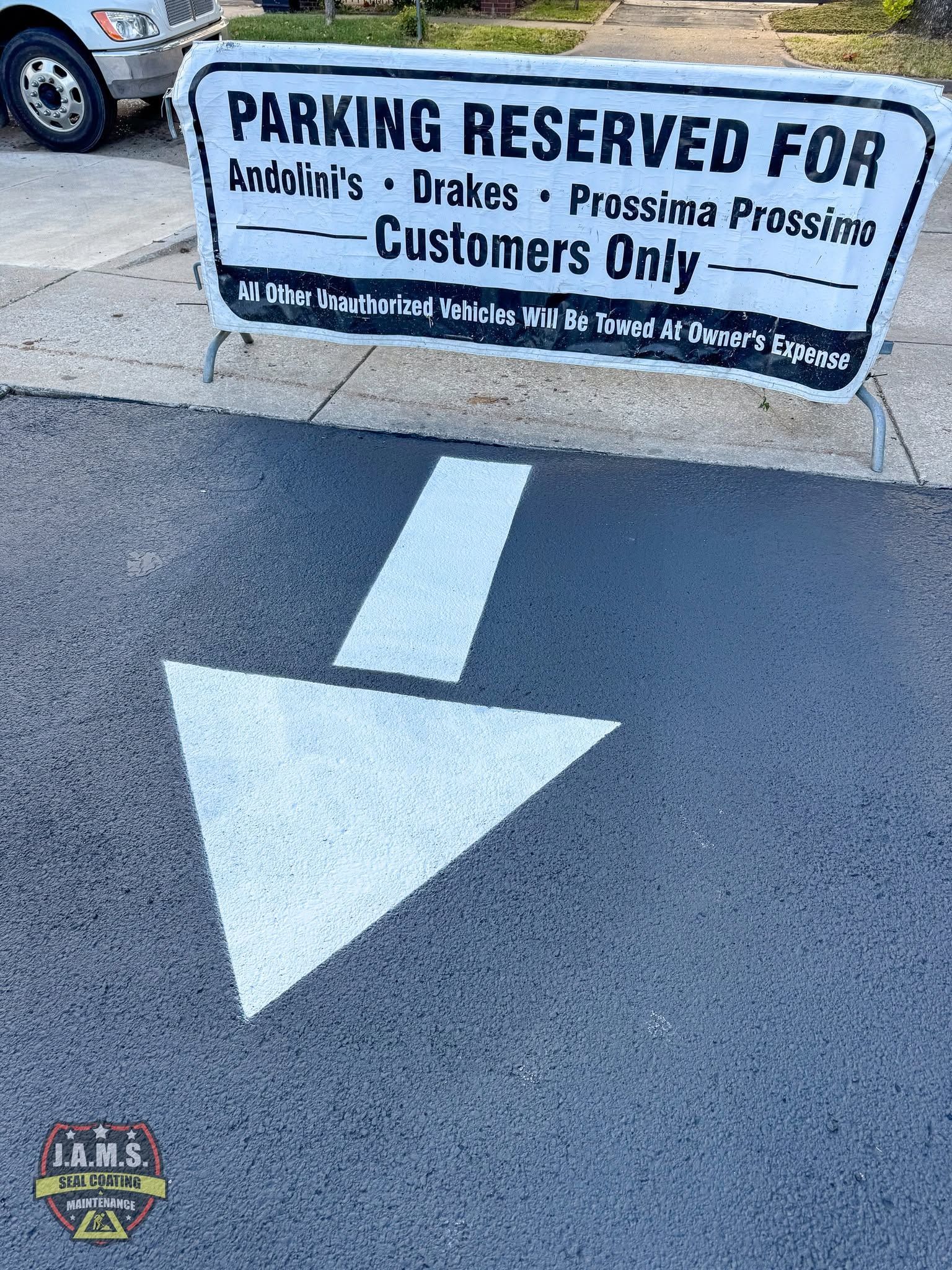 White arrow painted on asphalt pointing to a reserved parking sign for customers only.