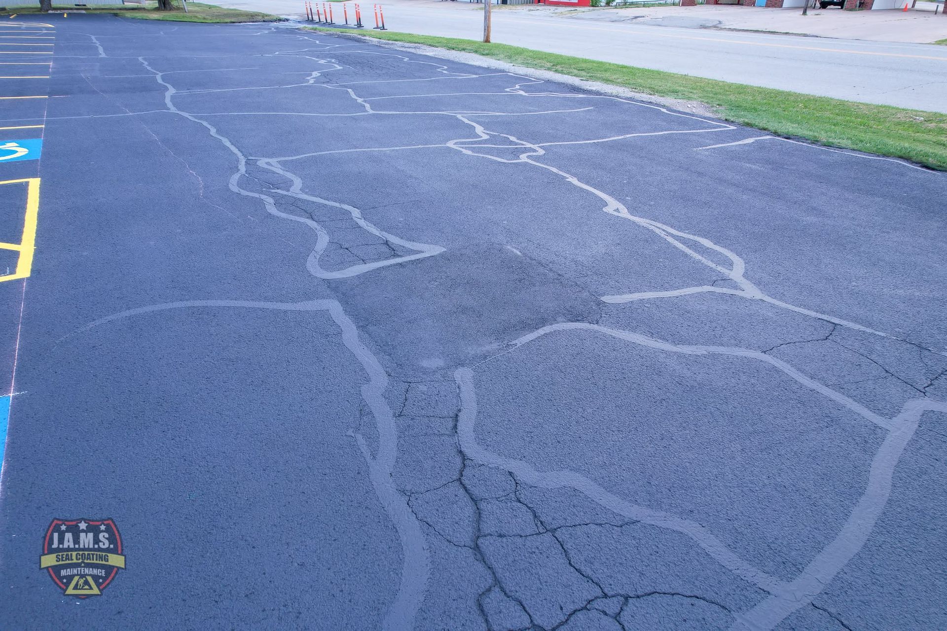 Cracked asphalt track with chalk outlines and a grassy field beside it