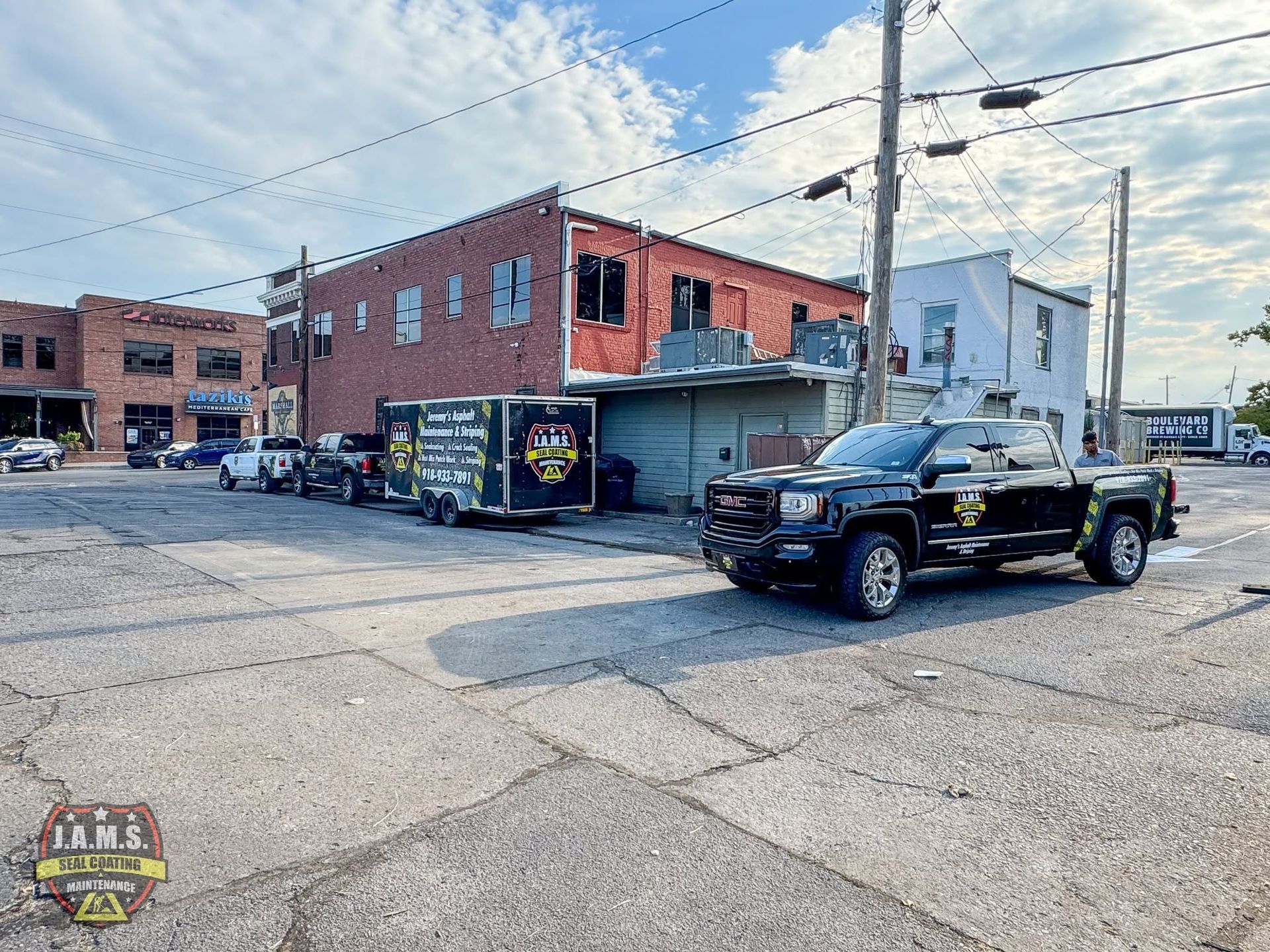 Black pickup truck parked beside a brick building on a city street corner.
