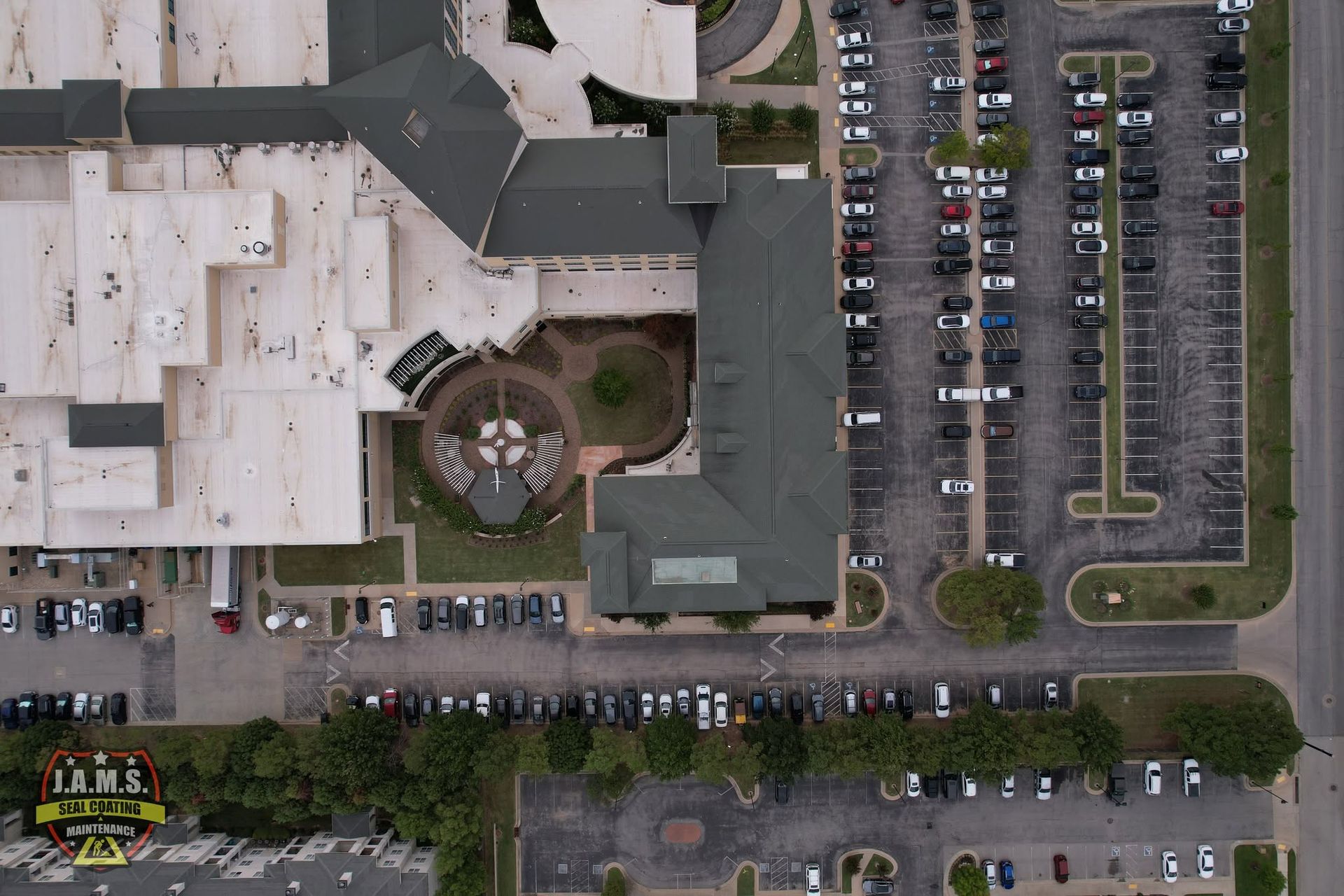 Aerial view of a large building, parking lots, and rows of parked cars along the streets