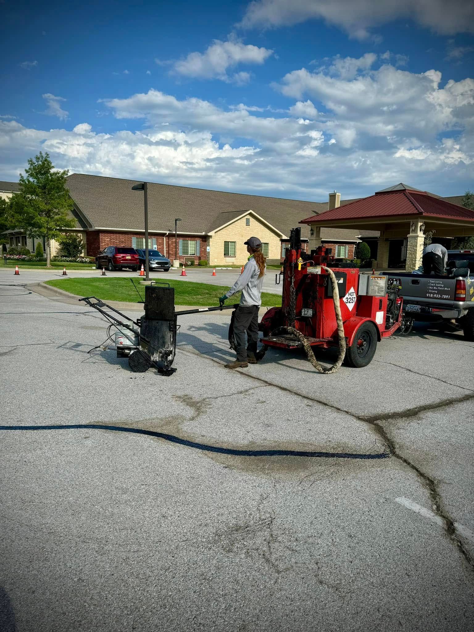 People near a red utility vehicle and gazebo in a cracked parking lot under a partly cloudy sky