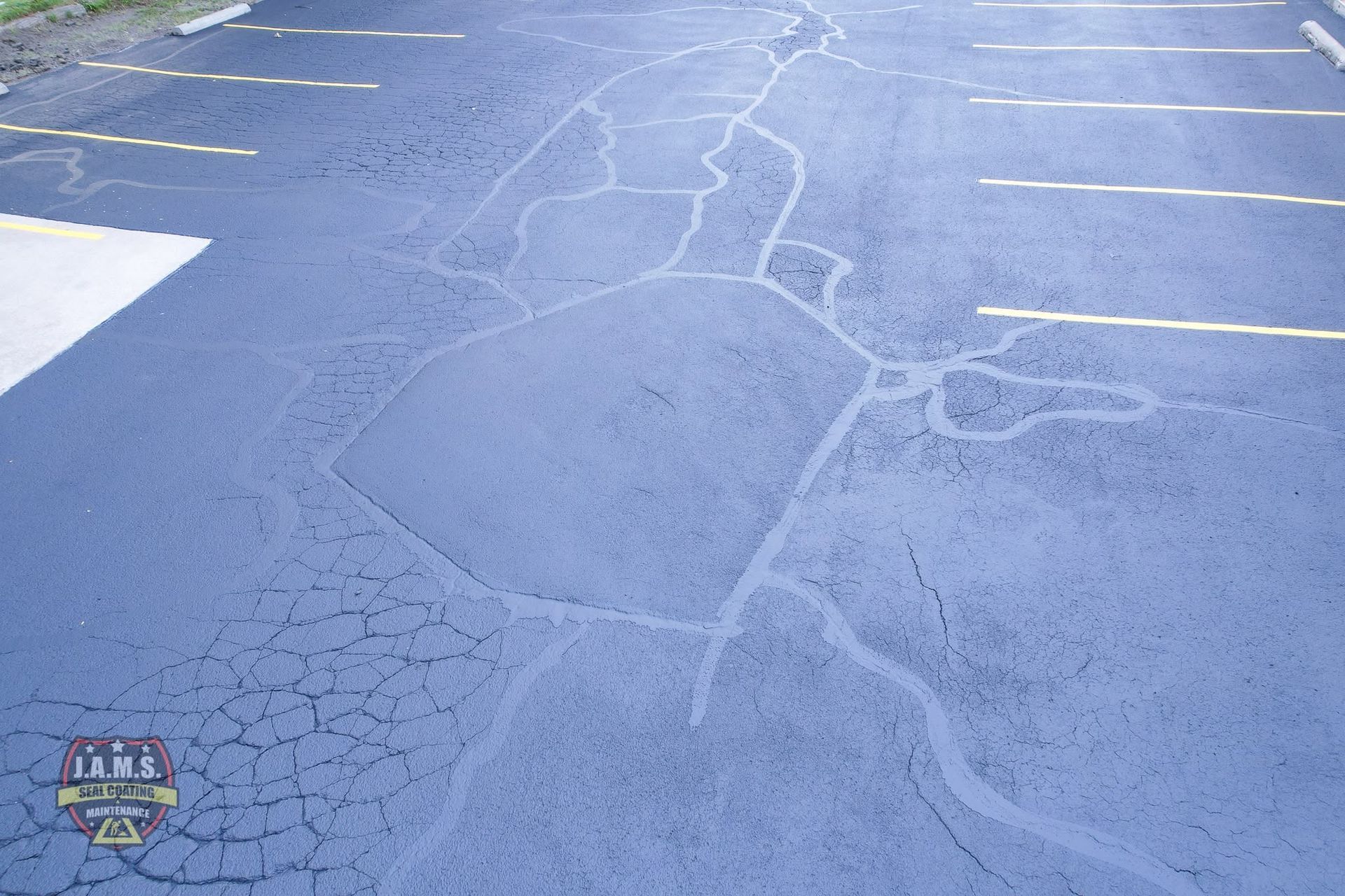 Cracked blue-painted parking lot pavement with white parking lines.