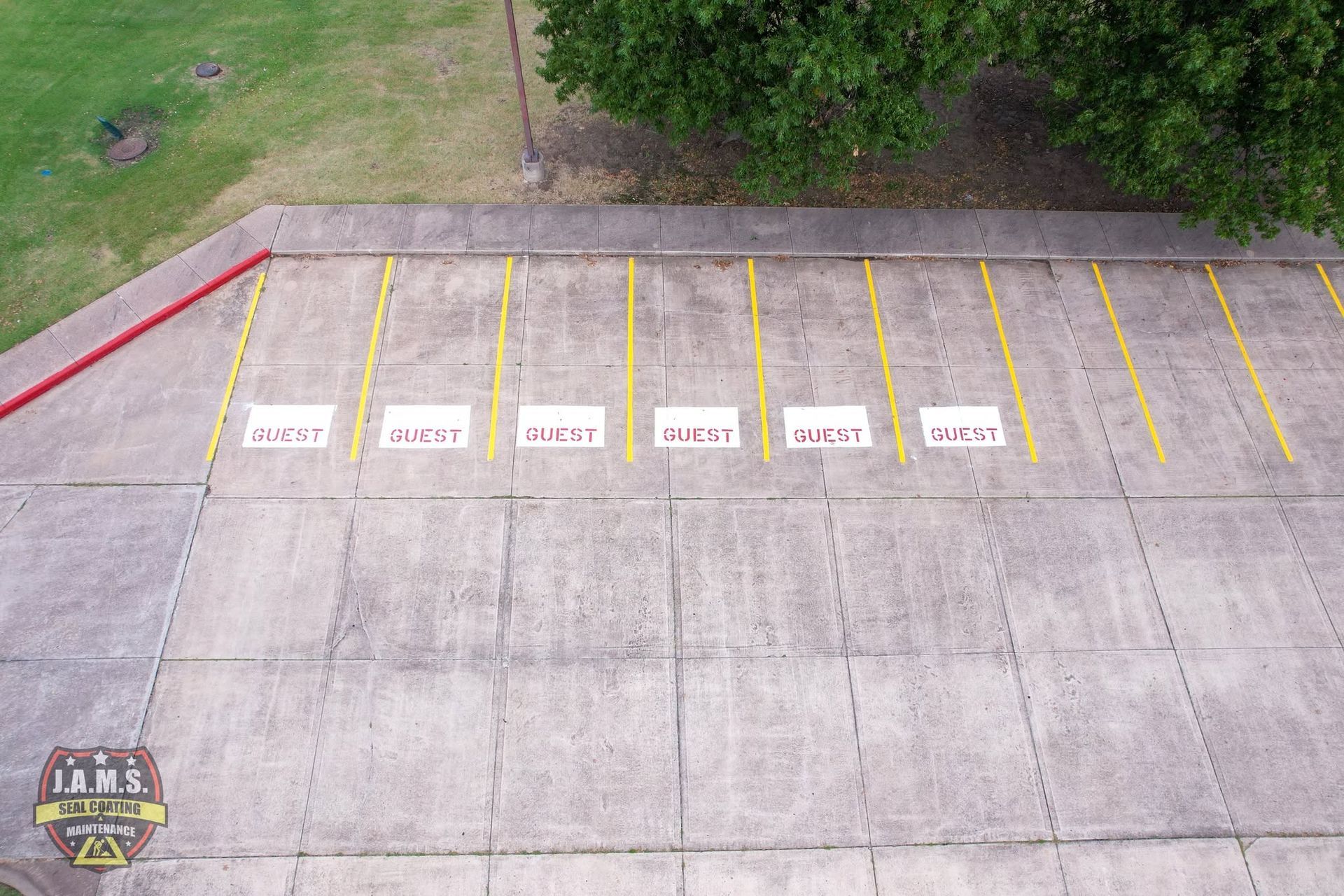 Aerial view of empty parking lot with yellow lines and numbered spaces marked by white signs.