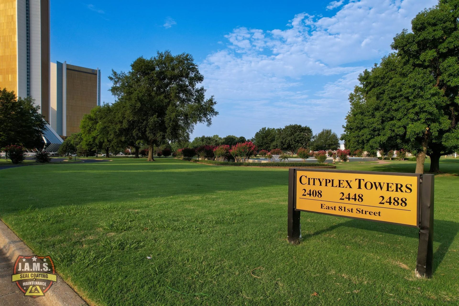Campus lawn with a sign for Cyprexx Towers and a tall building in the background