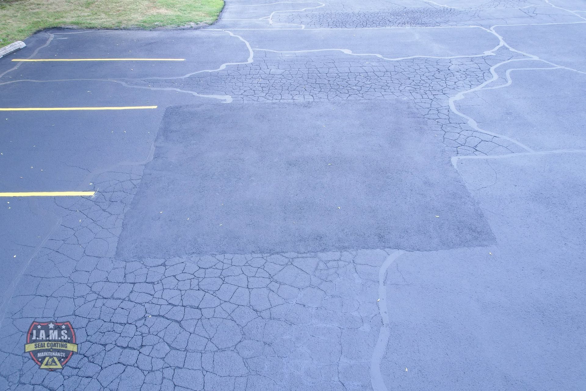Empty cracked blue-gray parking lot with faded yellow lines