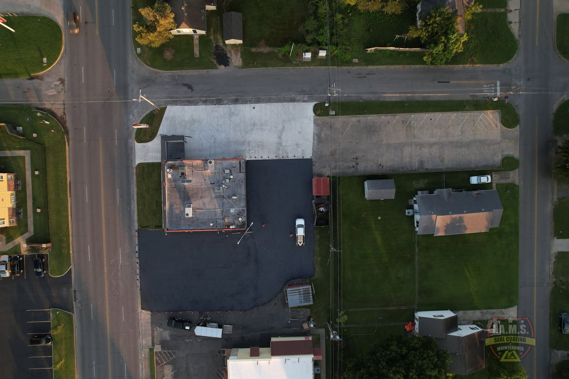 Aerial view of a residential block with houses, streets, parked cars, and green lawns