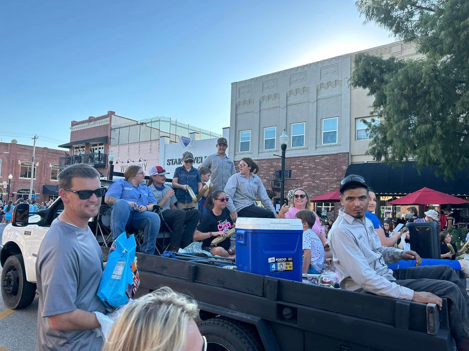People riding in a decorated truck at a street parade with spectators nearby