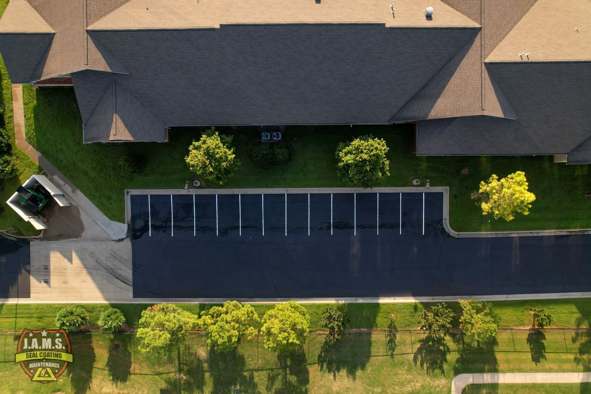 Aerial view of a house with a long dark driveway and greenery along the street