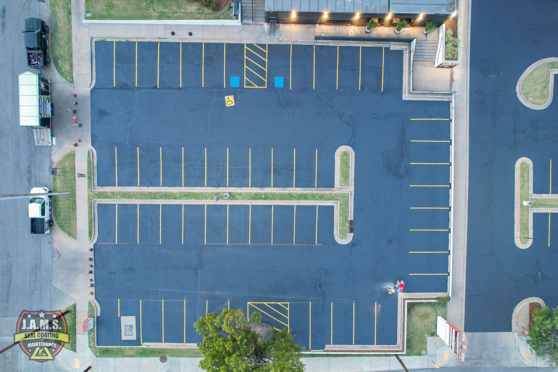 Aerial view of mostly empty parking lot with blue handicap spaces and trees along the edges