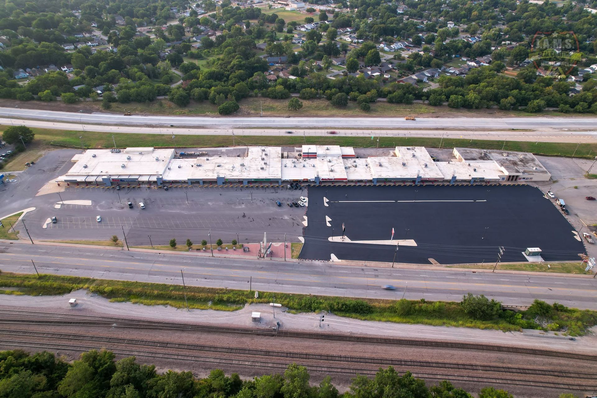 Aerial view of a large parking lot under construction beside a road and trees.