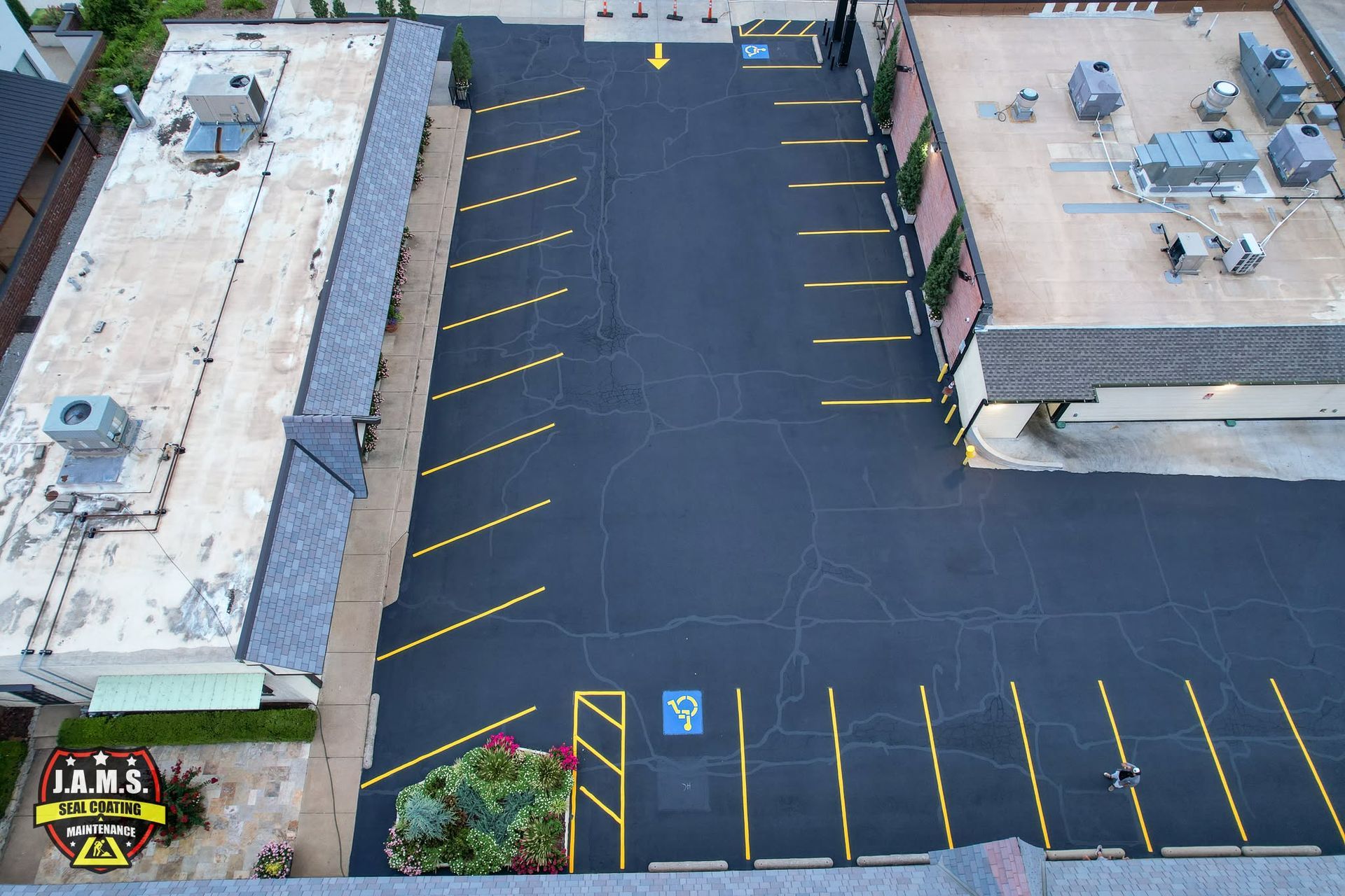 Aerial view of an empty blacktop parking lot with yellow lines between two buildings