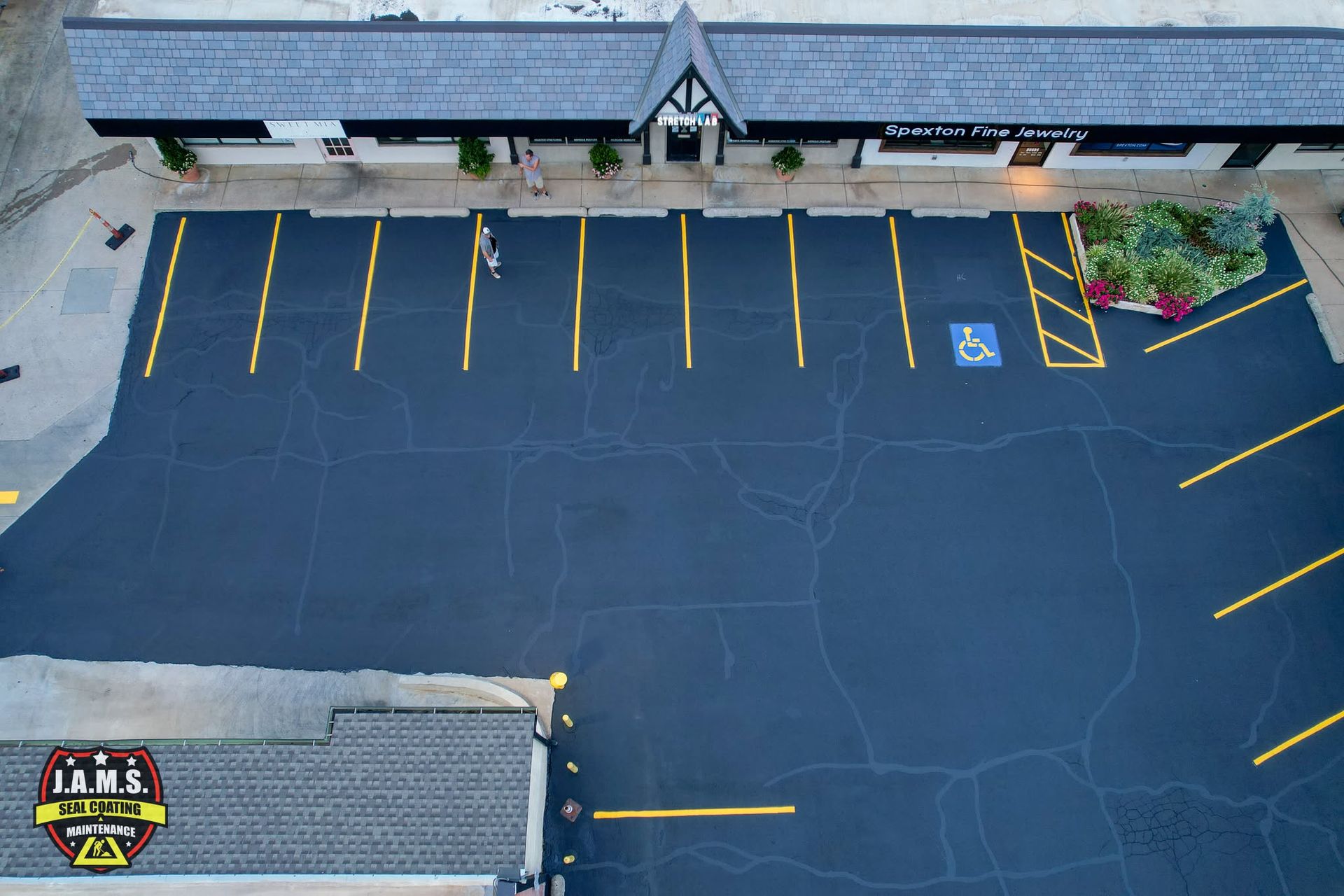 Empty parking lot with yellow lines beside a building and landscaped entrance