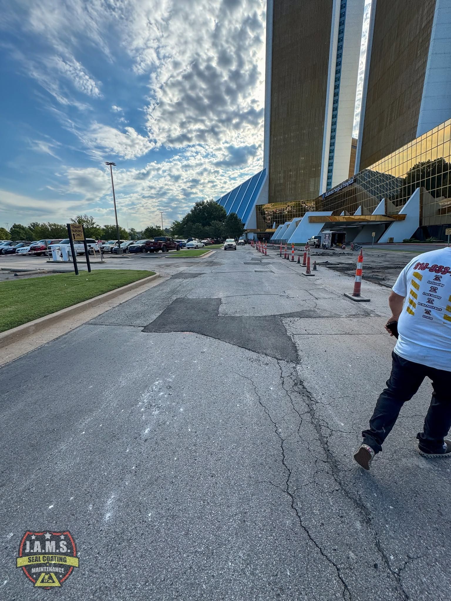 Walkway beside twin towers under a cloudy sky, with a person walking near traffic cones.