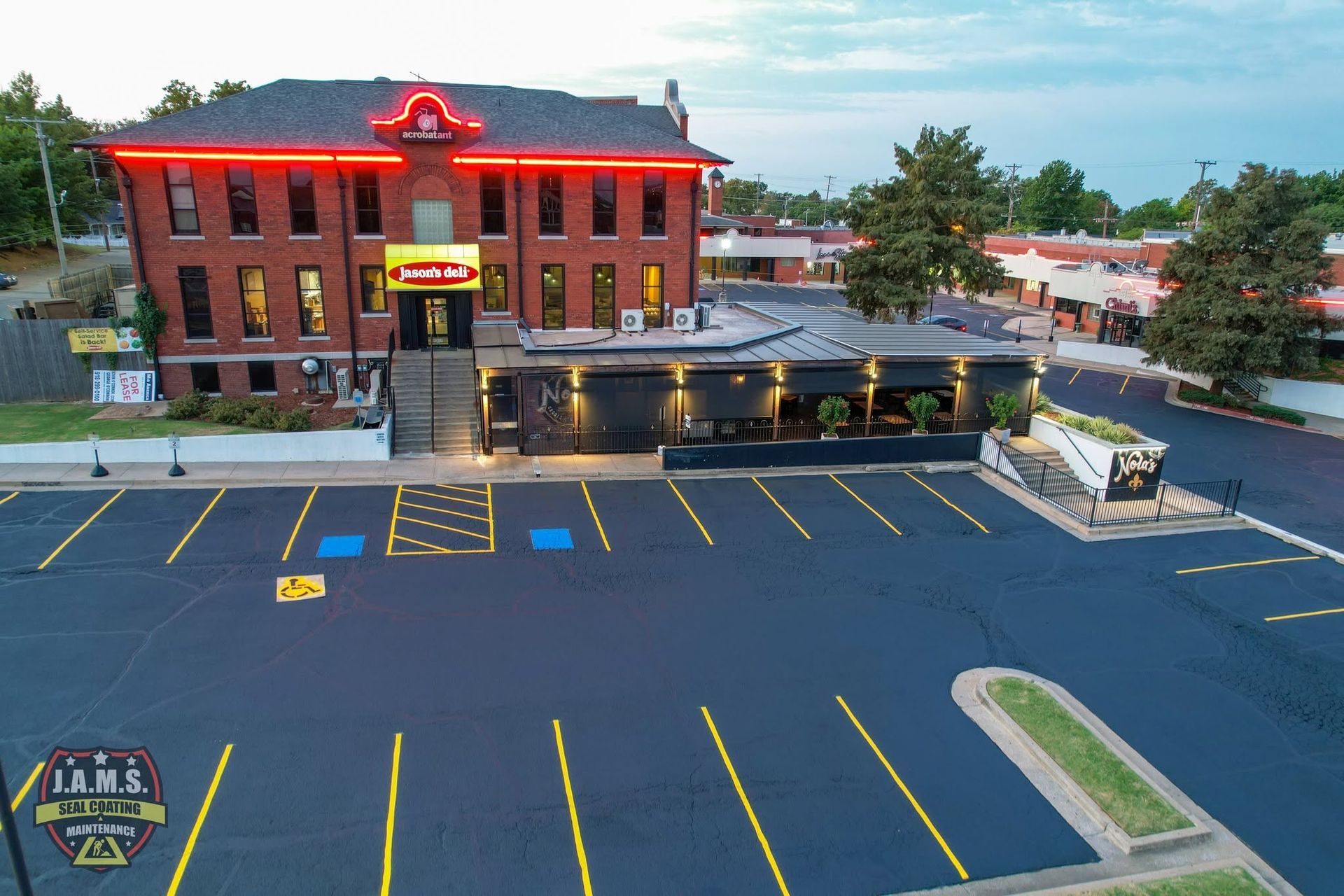 Brick hotel with red neon trim at dusk, beside an empty parking lot and entrance canopy.