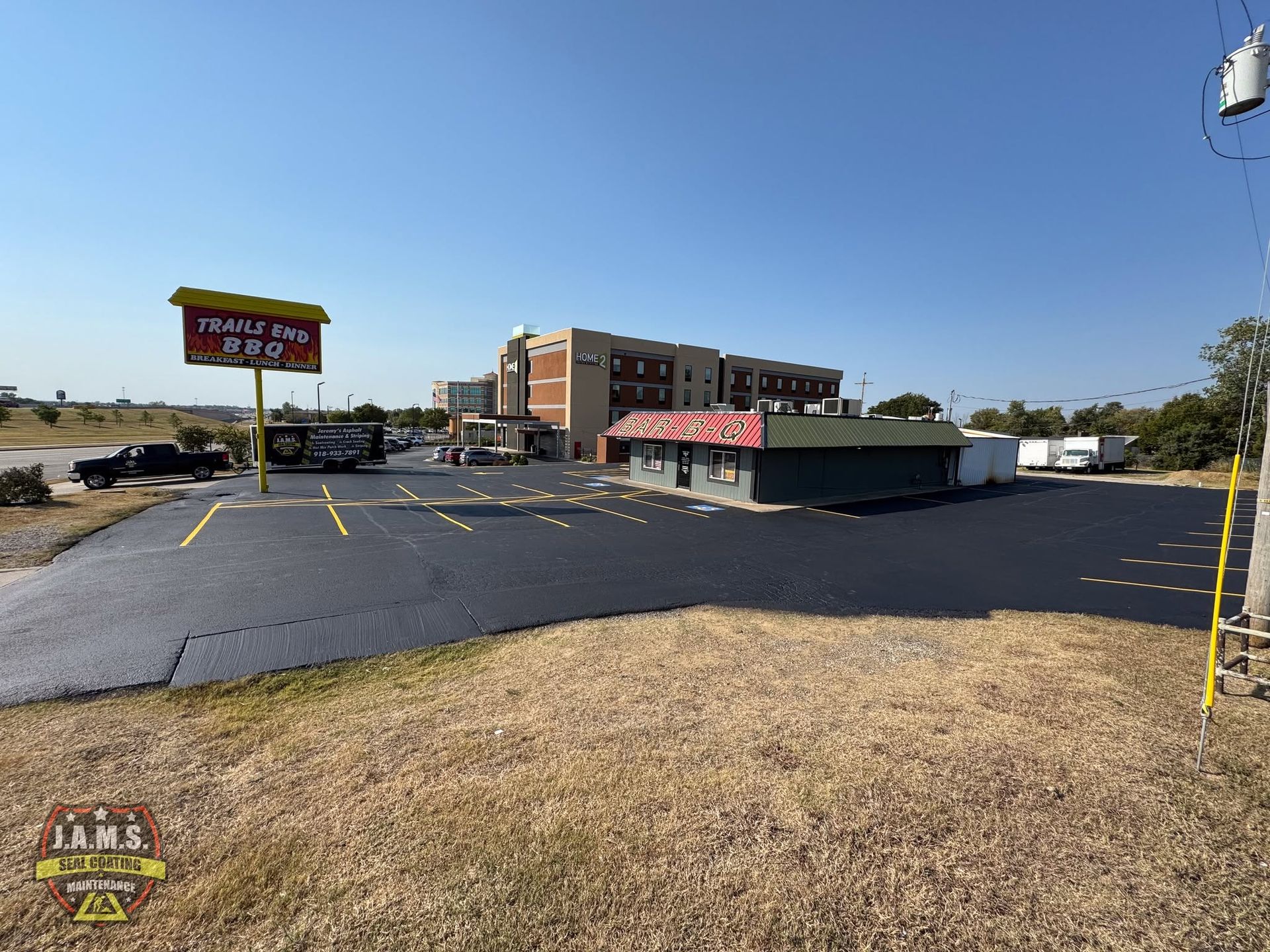Wide parking lot outside a low-rise motel and restaurant under a clear blue sky