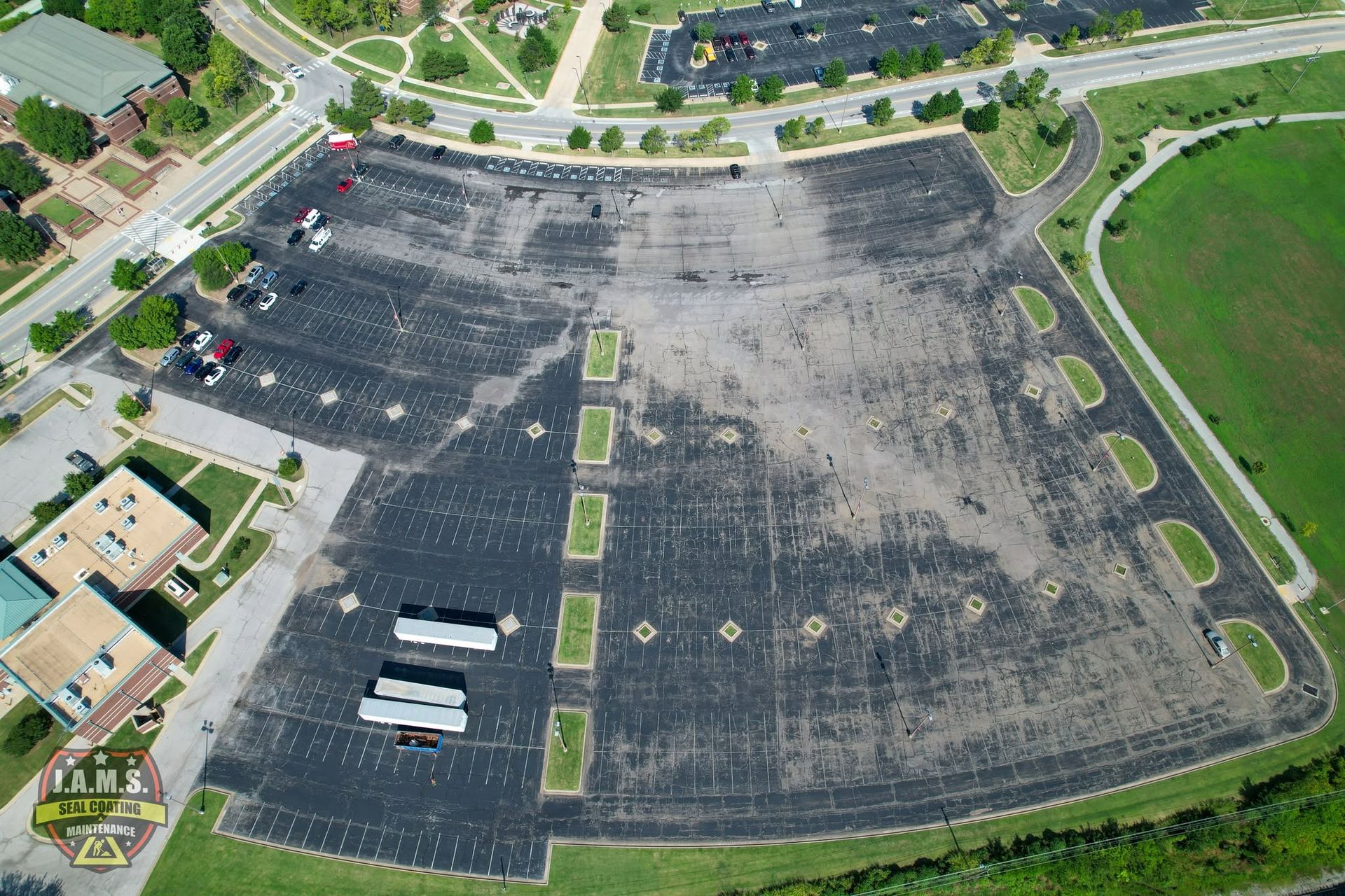 Aerial view of a large empty asphalt parking lot with painted lines and a few parked trailers