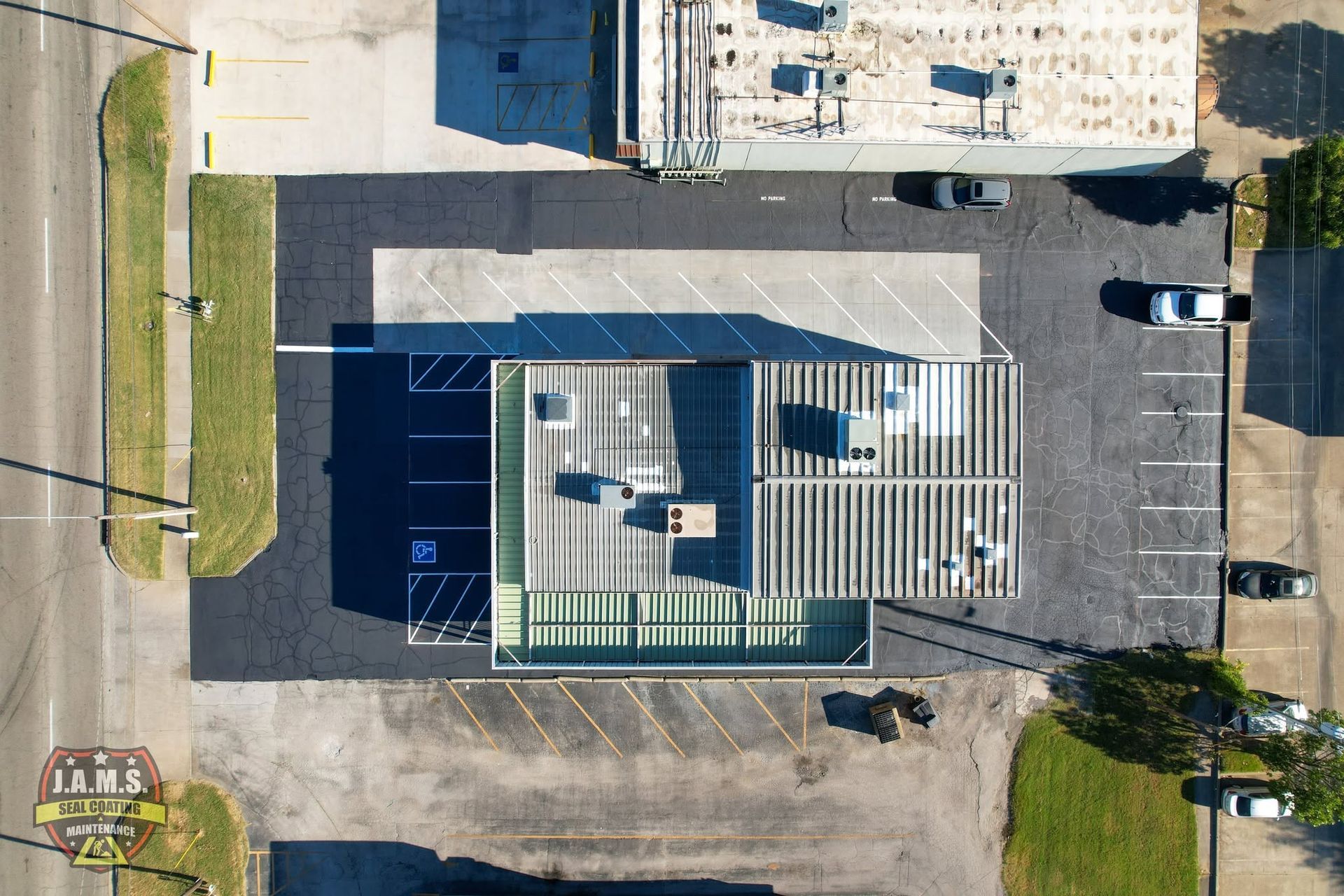Aerial view of a commercial parking lot with a flat-roofed building and a few parked vehicles.