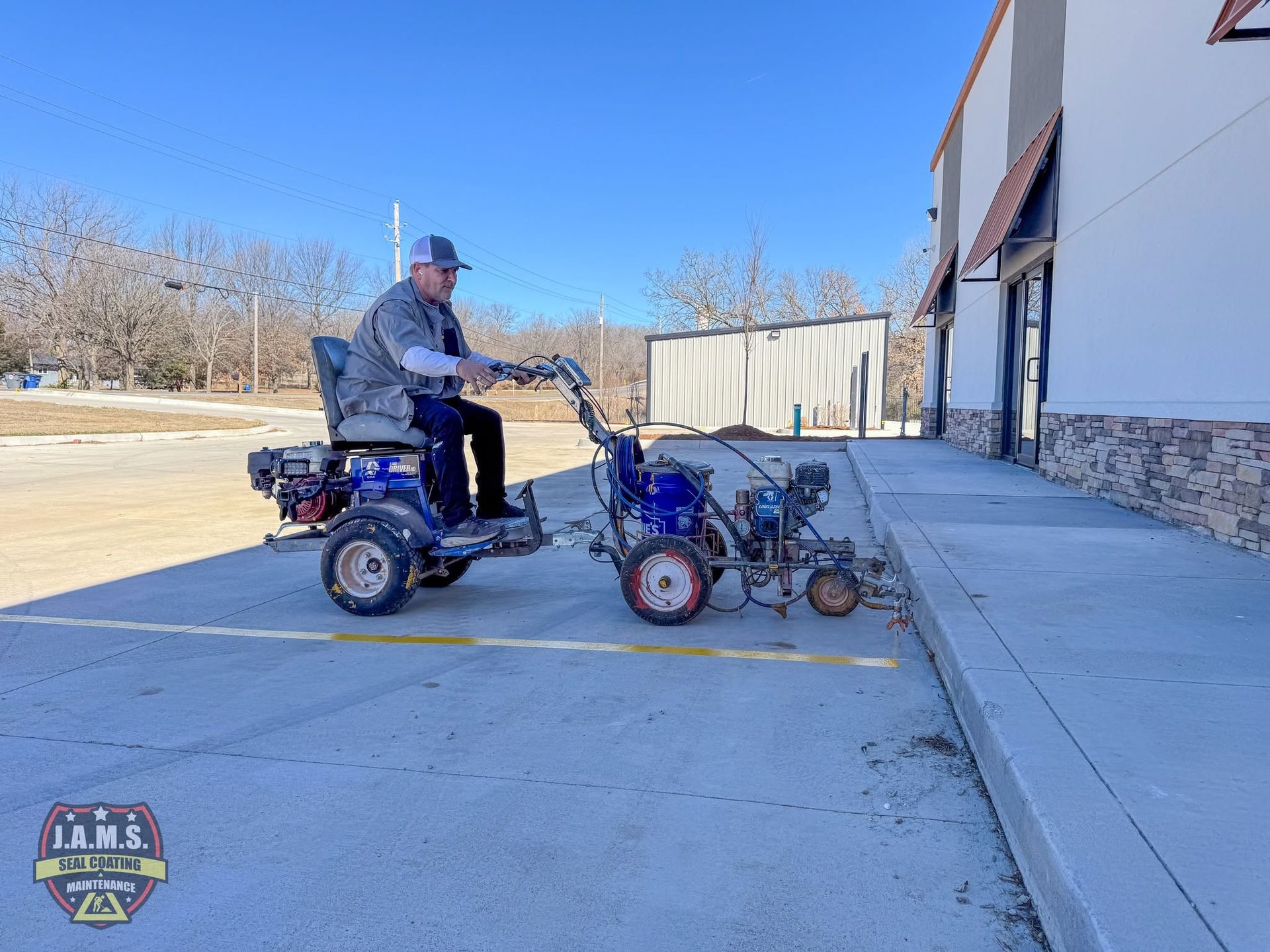 Man on a blue mobility scooter towing a small cart beside a building on a sunny day