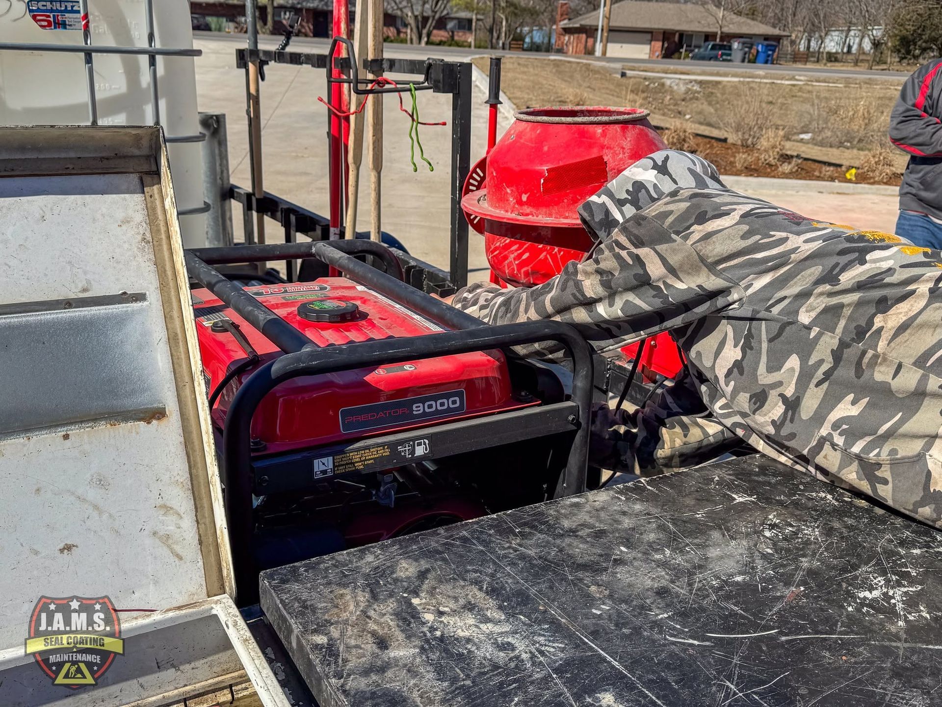 Person in camouflage crouches over a red portable generator on a truck bed.