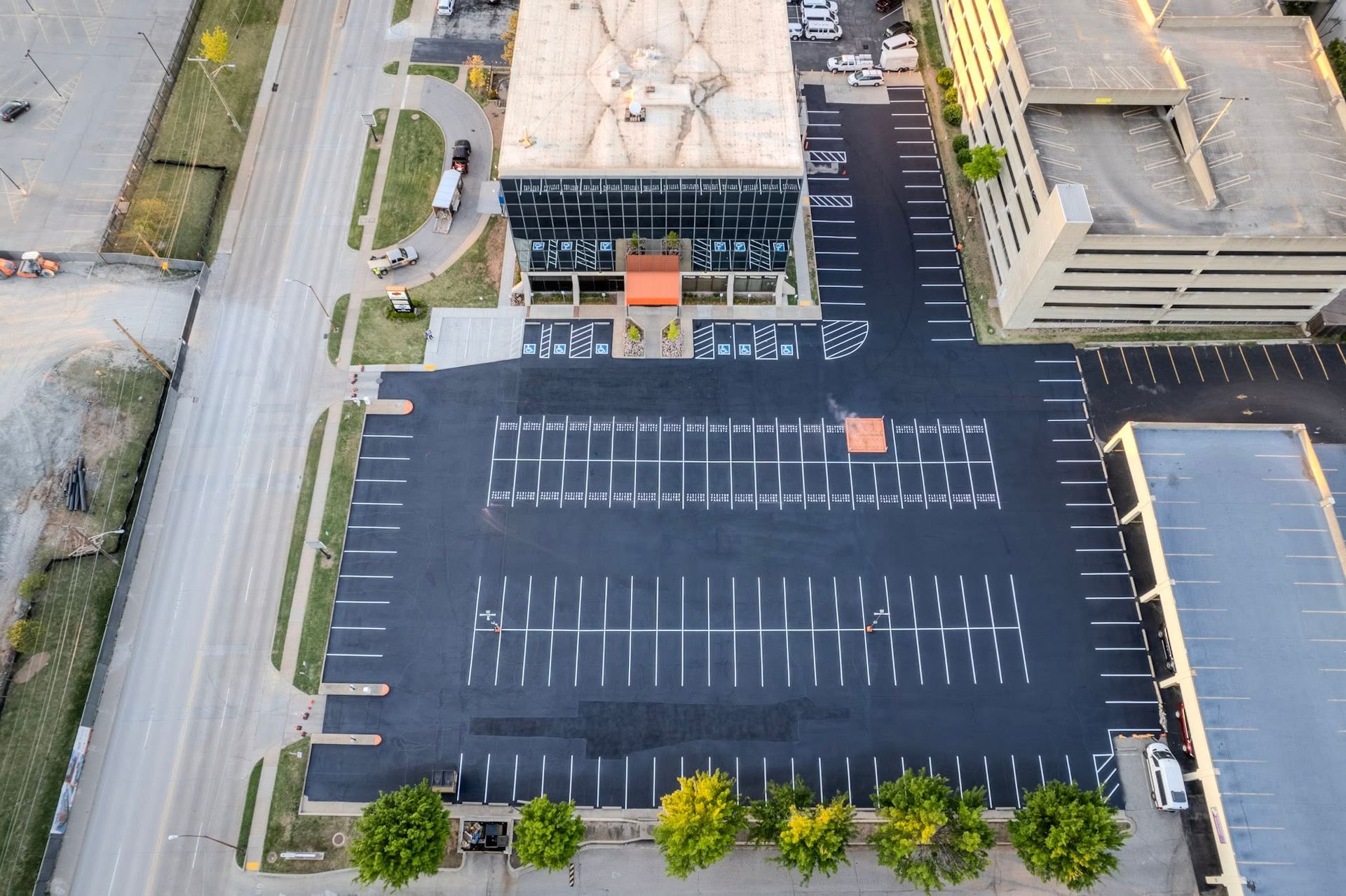 Aerial view of an empty parking lot beside a building and street.
