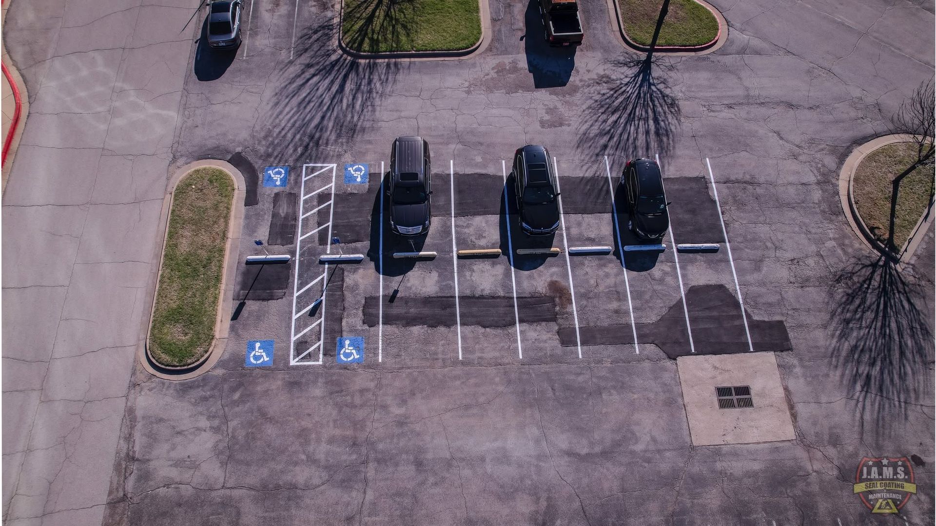 Aerial view of a mostly empty parking lot with a few cars and blue handicap parking spaces.