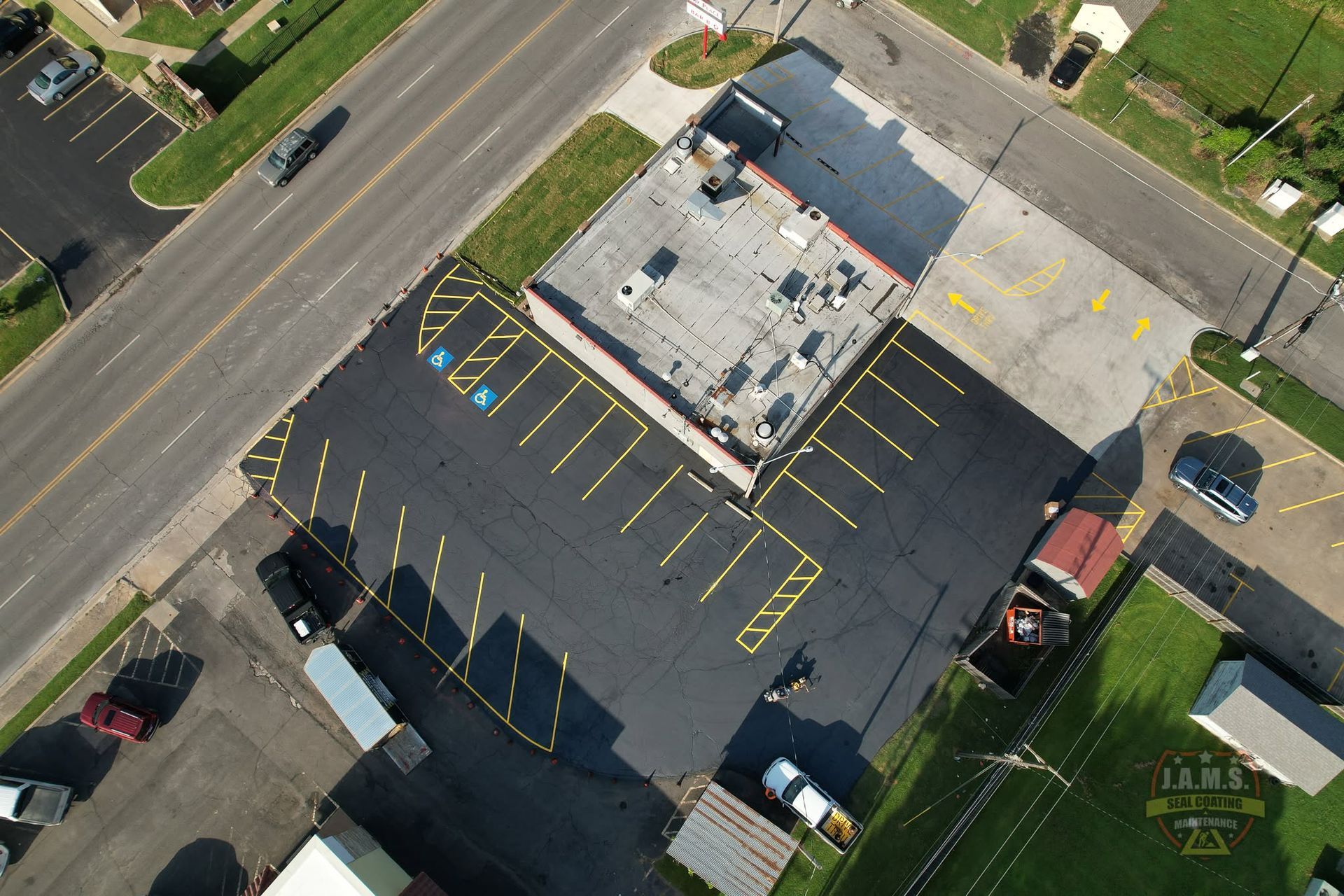 Aerial view of a mostly empty parking lot beside a commercial building and road