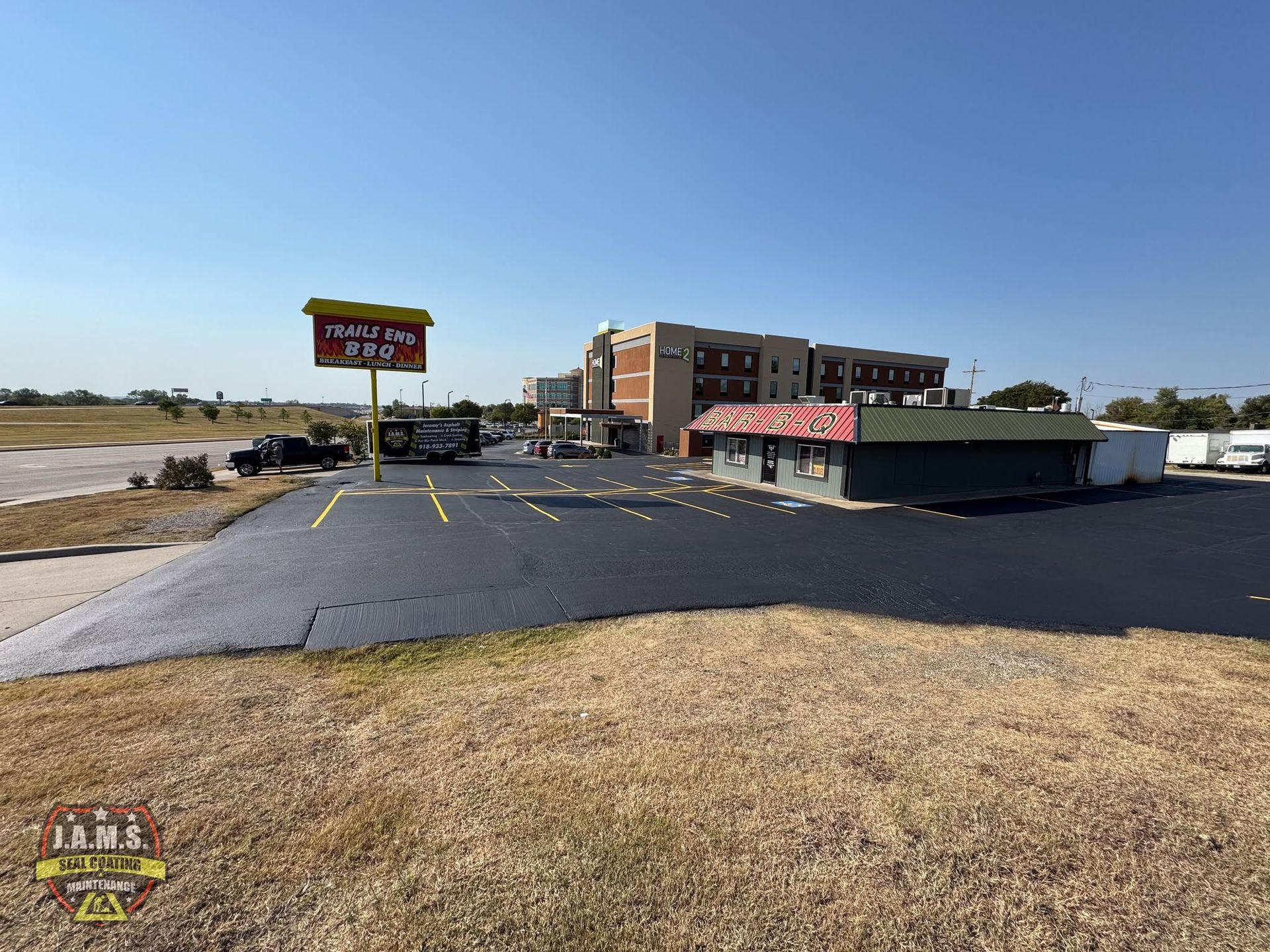 Parking lot outside a motel with a sign, low building, and open blue sky