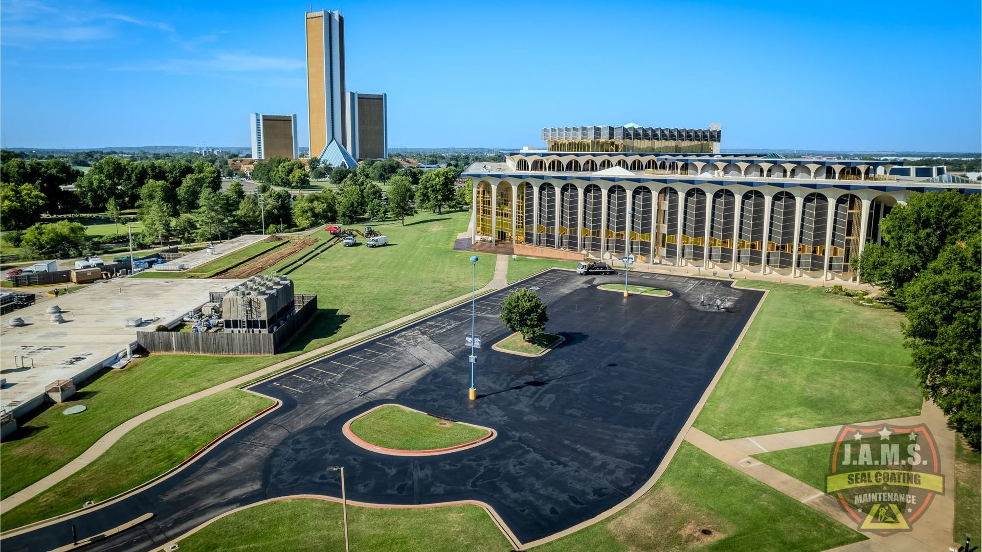 Large stone church beside a black reflecting pool, with a tall tower and green parkland in the background