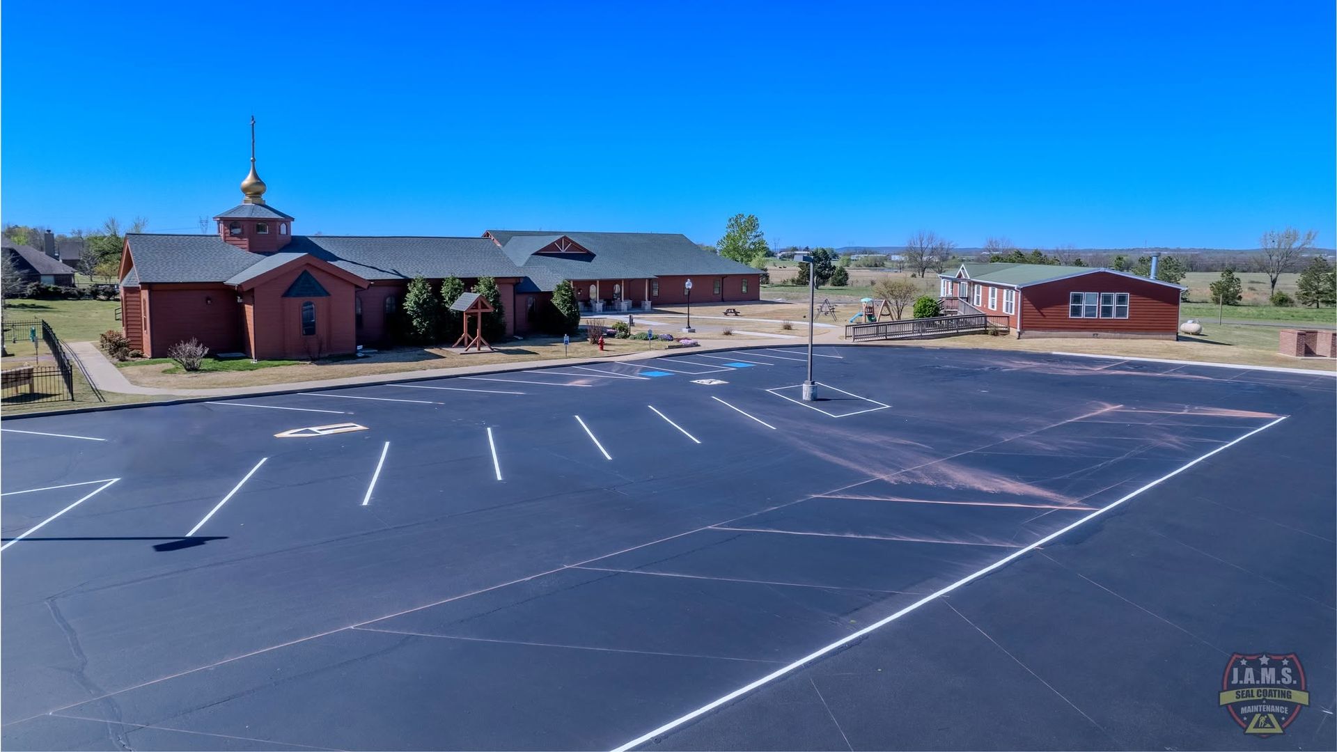 Empty parking lot beside a small red building under a clear blue sky