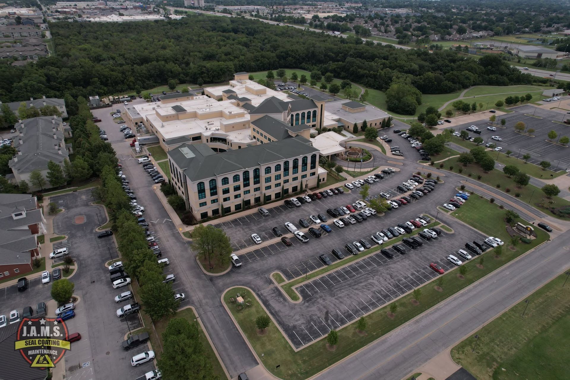 Aerial view of a large office complex with parking lots, roads, and surrounding greenery.
